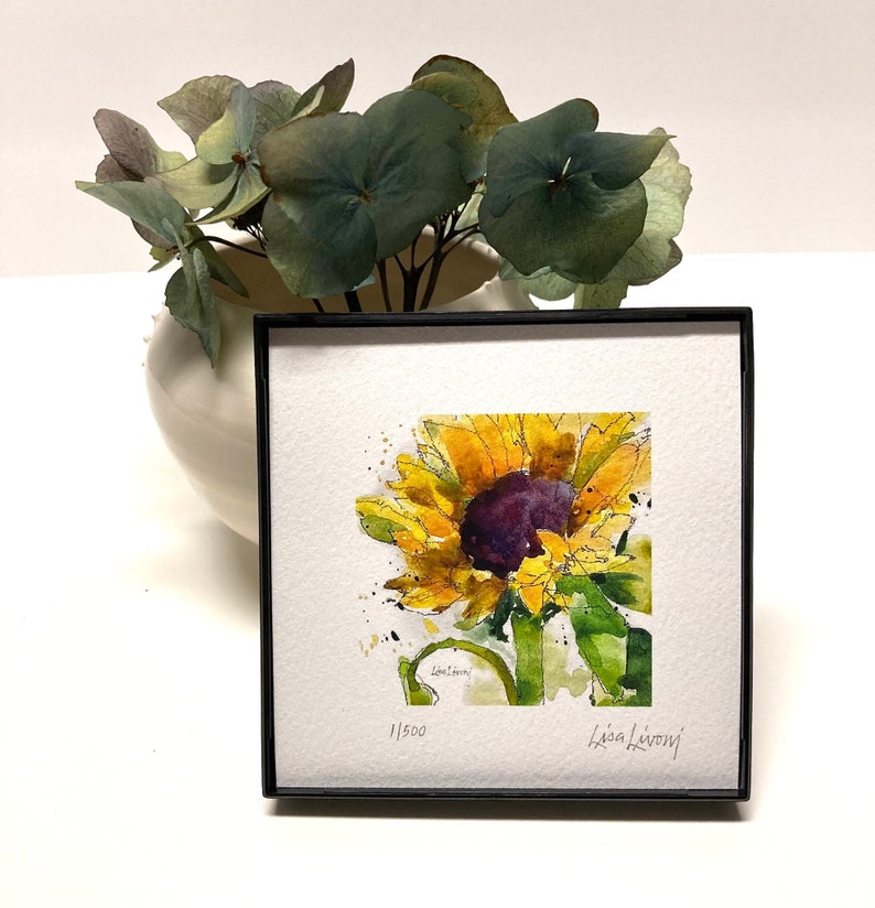May include: A framed watercolor painting of a sunflower with yellow petals and a dark purple center. The painting is signed "Lisa LeRoy" and numbered "1/500".