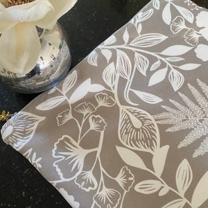 May include: A gray fabric pouch with a white floral pattern. The pouch has a zipper closure and is perfect for storing small items.