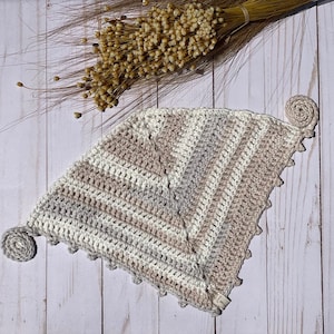 Puede incluir: Un gorro de punto de tri&aacute;ngulo con un patr&oacute;n de rayas en beige, blanco y gris. El gorro tiene un pomp&oacute;n de punto en cada esquina.
