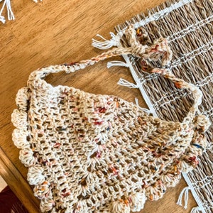 K&ouml;nnte beinhalten: Ein geh&auml;keltes beigefarbenes Tuch mit einem gewellten Rand und mehrfarbigen Flecken. Das Tuch ist mit einem zarten Stichmuster gearbeitet und hat einen lockeren, bohemian Stil.