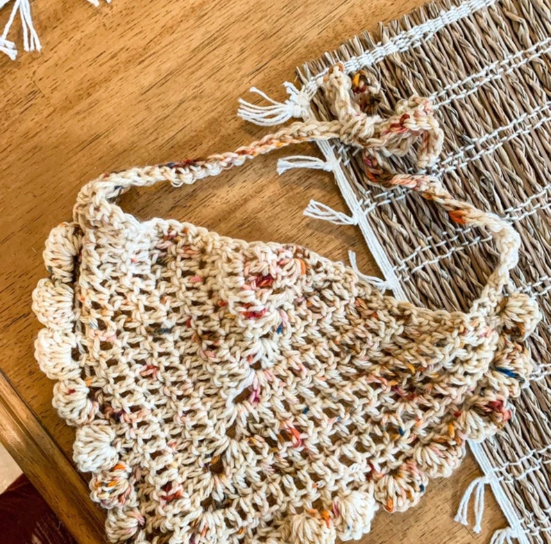 K&ouml;nnte beinhalten: Ein geh&auml;keltes beigefarbenes Tuch mit einem gewellten Rand und mehrfarbigen Flecken. Das Tuch ist mit einem zarten Stichmuster gearbeitet und hat einen lockeren, bohemian Stil.