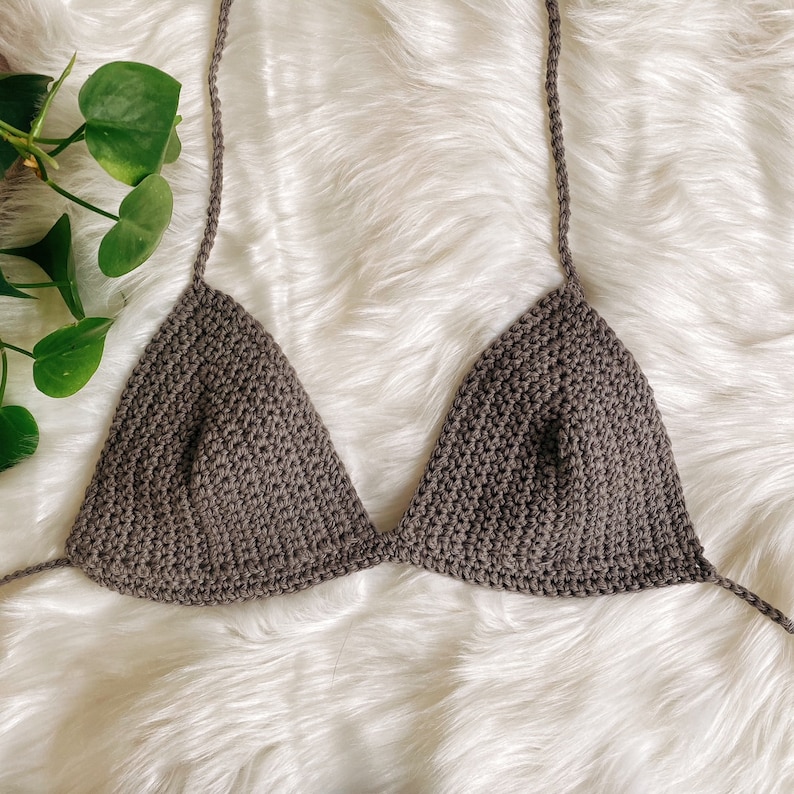 Pu&ograve; includere: Un top bikini triangolare in crochet marrone con spalline sottili.