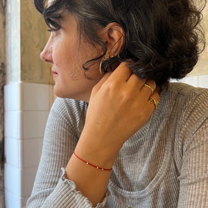 Handmade red string bracelet with a golden ball