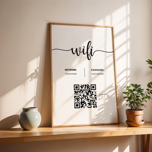 May include: A framed white poster with the word "wifi" in black cursive script. The poster has a black and white QR code and the words "Network" and "Password" with spaces for the user to write in their network name and password. The poster is on a wooden table with a light blue vase and a potted plant.