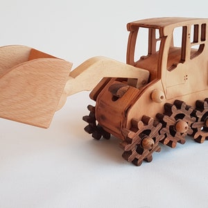 Peut inclure: Un jouet d'excavatrice en bois avec une pelle brune et une cabine détaillée. L'excavatrice a un ensemble d'engrenages bruns pour roues.