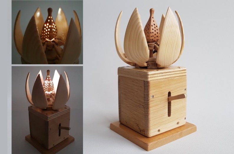 May include: A wooden sculpture of a flower with a light inside. The flower is made of multiple pieces of wood and has a small, round light in the centre. The flower is sitting on a wooden base with a lever on the side.