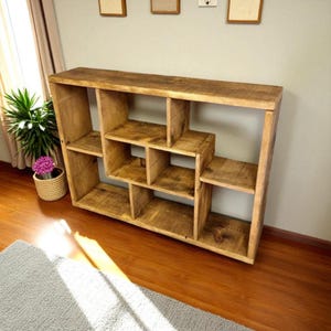 May include: A rustic wooden bookshelf with a unique geometric design. The shelves are arranged in a stepped pattern, creating multiple storage compartments. The wood has a natural, warm tone, and the bookshelf is freestanding.