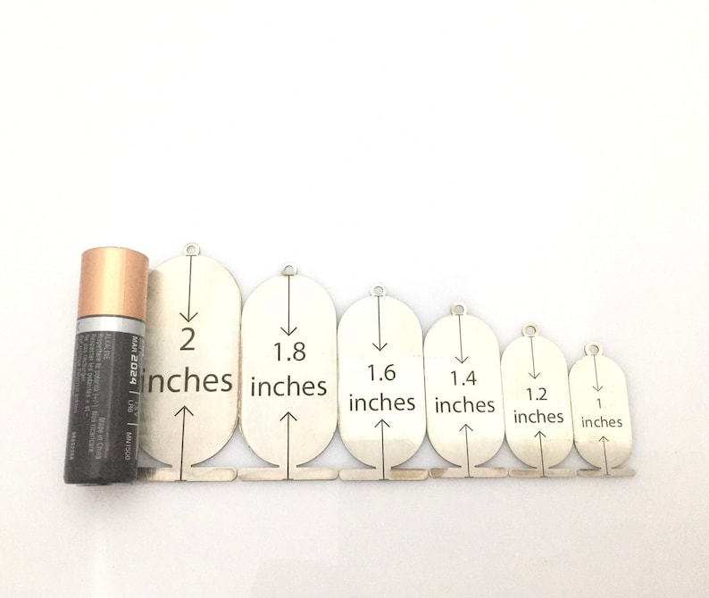 May include: Set of seven silver metal circles with arrows pointing down and measurements in inches: 2, 1.8, 1.6, 1.4, 1.2, and 1.