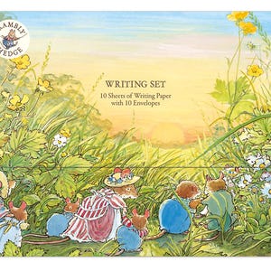 May include: A Brambly Hedge writing set featuring 10 sheets of writing paper and 10 envelopes. The packaging displays a colourful illustration of mice in a grassy meadow at sunset, with yellow flowers and green foliage surrounding the characters.