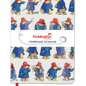 May include: A5 clothbound journal with illustrations of Paddington Bear in a blue coat and red hat. The journal cover features multiple images of Paddington Bear in different poses. The text "Paddington Since 1968 Clothbound A5 Journal" is also visible.