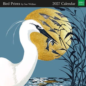 May include: A 2027 calendar titled Bird Prints by Sue Welfare featuring a white egret holding a fish in its beak against a large gold circular sun. The scene includes dark blue reeds and water reflections on a muted blue background with a Zero Plastic label.