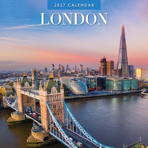 May include: A 2027 London calendar featuring a high-angle view of Tower Bridge in the foreground with the River Thames and the city skyline, including The Shard, visible in the background under a soft sunset sky with pink and blue hues.