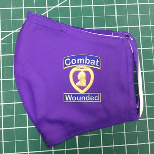 May include: Purple face mask with a gold embroidered heart and the words "Combat Wounded".