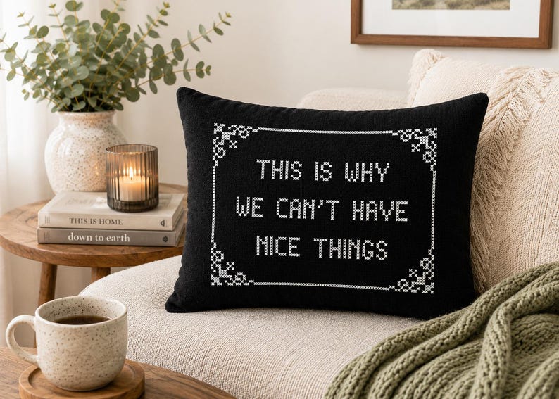 May include: A rectangular black throw pillow featuring white cross-stitch embroidery. The design includes a decorative border and the text "THIS IS WHY WE CAN'T HAVE NICE THINGS" centered in the middle, mimicking a traditional sampler style.
