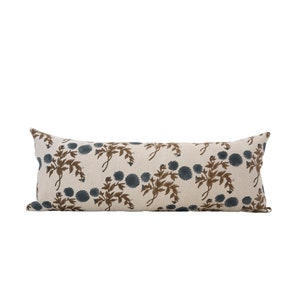 May include: A long, rectangular cushion with a white background and a floral pattern in shades of brown and blue.