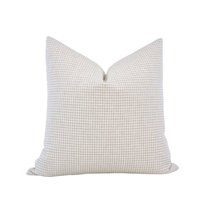 May include: A beige and white gingham pillow with a square pattern.