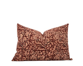 May include: A decorative pillow with a floral pattern in shades of red, orange, and cream. The pillow is made of a soft, textured fabric.