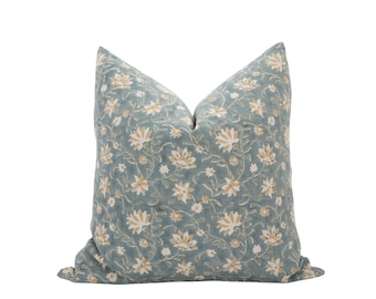 Peut inclure: Un coussin de décoration bleu et crème à motifs floraux. Le coussin est fait d'un tissu doux et texturé.