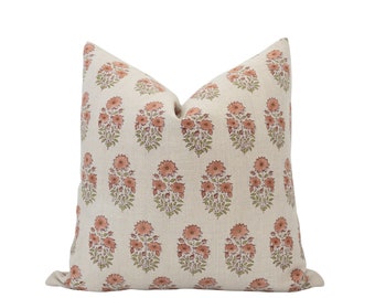 May include: A cream-colored throw pillow with a floral pattern in shades of pink and green. The pillow is made of linen and has a subtle texture.