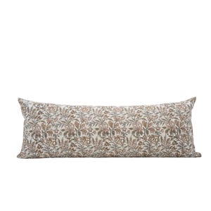 Peut inclure: Un long coussin rectangulaire avec un motif floral. Le coussin pr&eacute;sente un fond cr&egrave;me avec un motif r&eacute;p&eacute;t&eacute; de fleurs et de feuilles marron, grises et vertes. Le coussin est con&ccedil;u pour un usage d&eacute;coratif.