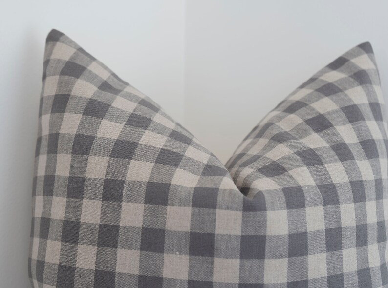 May include: A gray and white gingham pillow cover. The pillow cover is made of a soft, woven fabric.
