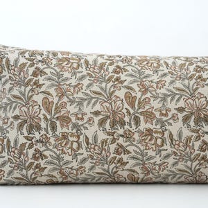 Peut inclure: Un long coussin rectangulaire avec un motif floral. Le coussin pr&eacute;sente un fond cr&egrave;me avec un motif r&eacute;p&eacute;t&eacute; de fleurs marron et roses et de feuilles vertes. C'est un article d&eacute;coratif.