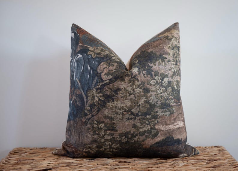 May include: Decorative throw pillow with a vintage-style botanical print in shades of brown, green, and blue. The pillow features a detailed floral and landscape design, adding a touch of classic elegance to home decor.