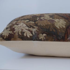 Puede incluir: Un coj&iacute;n rectangular con una base color crema y una parte superior estampada. La parte superior presenta un dise&ntilde;o detallado en tonos de marr&oacute;n, beige y burdeos, que representa un motivo floral o de follaje. El coj&iacute;n es probablemente para la decoraci&oacute;n del hogar.