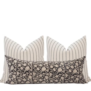 May include: Two white and black striped pillow covers with a black and white floral patterned lumbar pillow in the center.