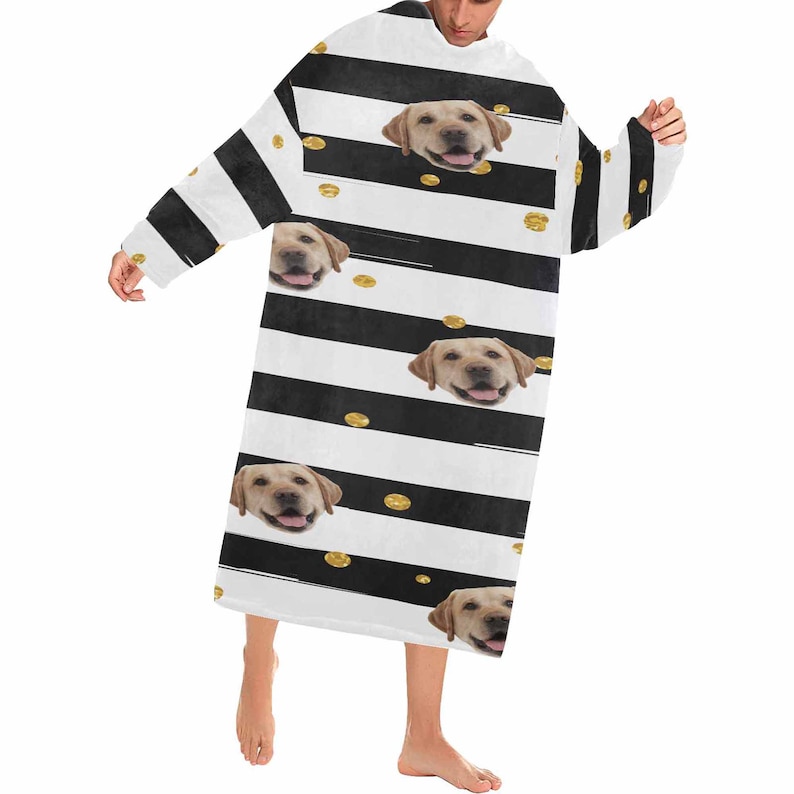 May include: A black and white striped wearable blanket featuring smiling Labrador Retriever faces and gold-colored polka dots. The blanket has long sleeves and a relaxed fit, perfect for lounging.