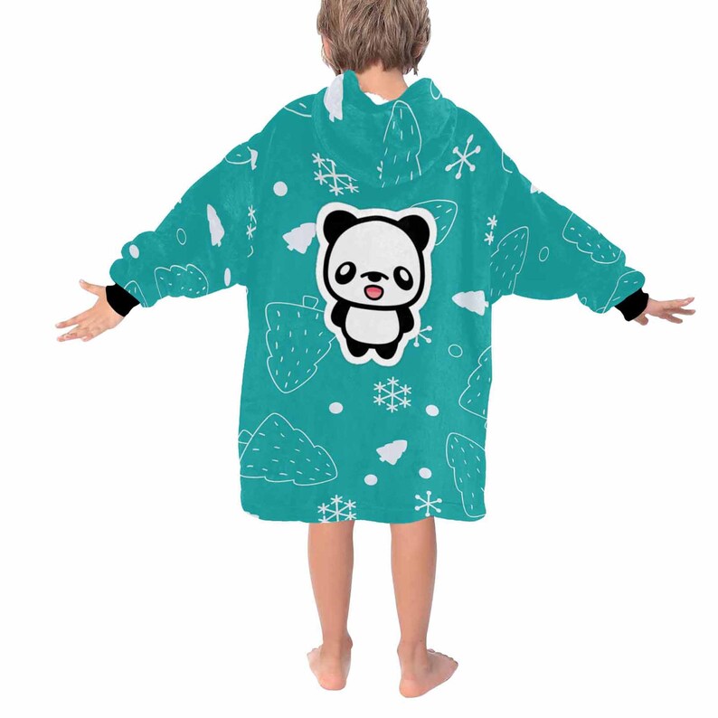 K&ouml;nnte beinhalten: Eine t&uuml;rkisfarbene Kapuzen-Decke mit einem Panda-B&auml;ren-Motiv auf dem R&uuml;cken. Die Decke hat ein Muster aus wei&szlig;en B&auml;umen, Schneeflocken und Punkten. Die &Auml;rmel haben schwarze B&uuml;ndchen. Das Kind tr&auml;gt die Decke.
