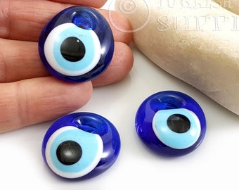 May include: Three blue glass evil eye charms with white and light blue centers and black pupils. The charms are round and have a hole at the top for hanging.
