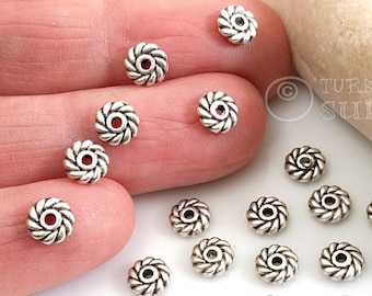 May include: A close-up of a pile of silver-toned metal beads with a rope-like design. The beads are about 1/2 inch in diameter and have a hole in the center for stringing.