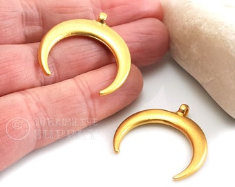 May include: Two gold-colored crescent moon charms. Each charm has a loop at the top for stringing. The charms have a matte finish and are likely made of metal. The charms are for jewelry making.