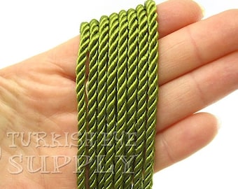 May include: A close-up of a bundle of olive green twisted cord. The cord is made of a soft, silky material and is perfect for crafting projects.