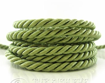 May include: A close-up of a spool of green twisted cord. The cord is made of a soft, silky material and is perfect for crafting projects.
