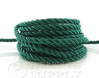 May include: A spool of dark green twisted cord. The cord is made of a soft, silky material.
