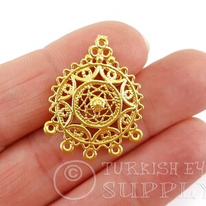 May include: Gold filigree pendant featuring a circular design with three loops at the bottom. The pendant is crafted from metal and boasts a delicate, intricate pattern.