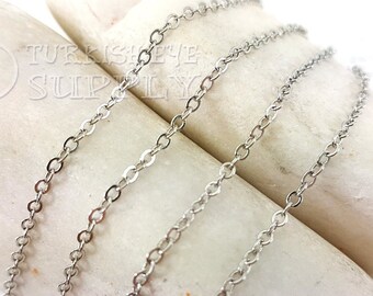 May include: Three silver chains of different lengths and thicknesses, laid out on a white surface.