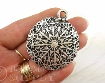 May include: Silver pendant with a detailed, intricate, circular design. The pendant features a starburst pattern with a raised center.