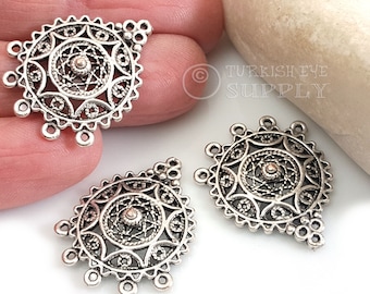 May include: Three silver filigree pendant charms with a circular design and five loops on the top. The charms are on a white surface.
