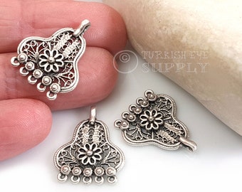 May include: Two silver filigree pendant charms with a flower design and a loop at the top. Each charm has a row of small silver beads at the bottom.