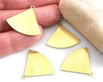Può includere: Quattro ciondoli in metallo dorato a forma di triangolo con un anello in cima. I ciondoli sono su una superficie bianca.