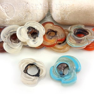 May include: Assortment of eight colorful glass flower-shaped beads with a hole in the center. The beads are made of layered glass with different colors and patterns.