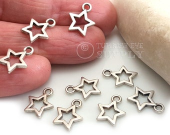 May include: Ten silver-toned star-shaped charms with a loop at the top. The charms are arranged on a white surface.
