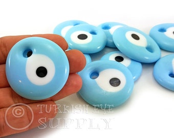 May include: A group of ten light blue evil eye charms with white and black eyes. The charms have a hole for stringing.