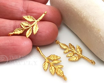 May include: Three gold-toned metal leaf charms with a loop at the top and bottom. The charms are in the shape of a branch with leaves.