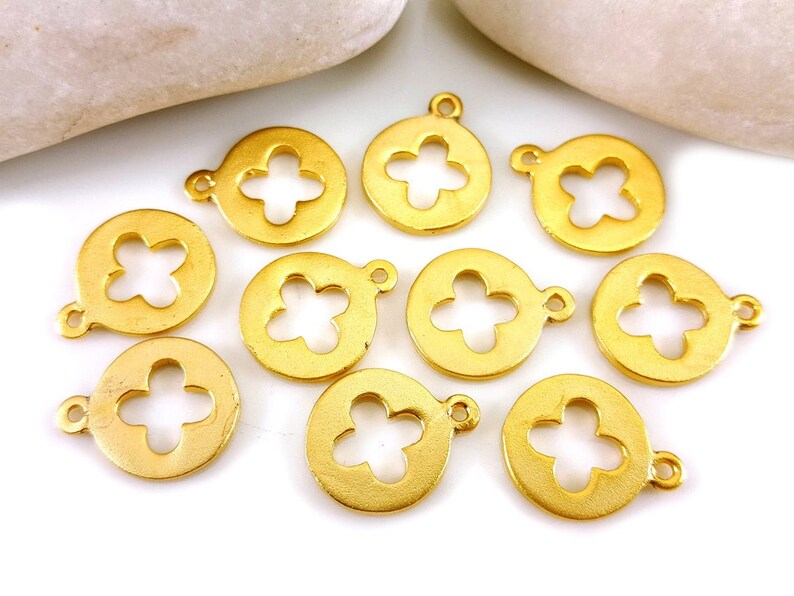 May include: Ten gold-colored metal charms with a flower cutout design. Each charm has a loop for attaching to jewelry or other crafts.