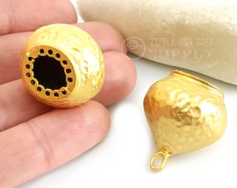 May include: Two gold-toned metal pendant charms with a hammered texture. One charm has a round shape with a hole in the center, while the other charm has a teardrop shape with a loop at the top.