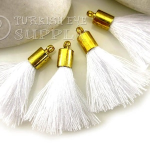 May include: Four white tassel trim with gold metal caps. The tassels are made of soft, silky threads and are perfect for adding a touch of elegance to any project.